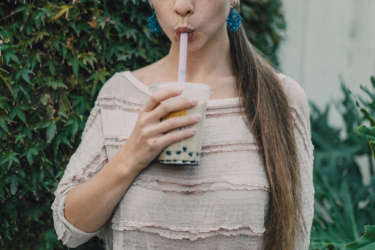 A young woman savoring a delicious bubble tea in an outdoor setting, displaying a relaxed lifestyle vibe.