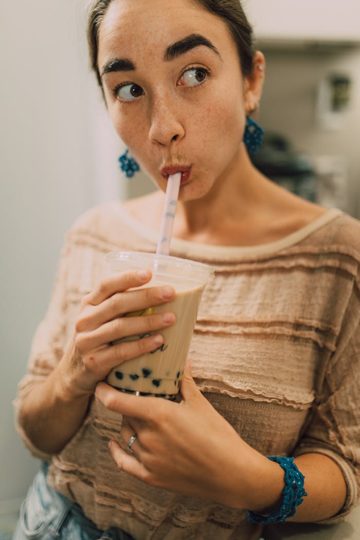 A woman enjoying a refreshing bubble tea with tapioca pearls, captured in a cozy indoor setting.